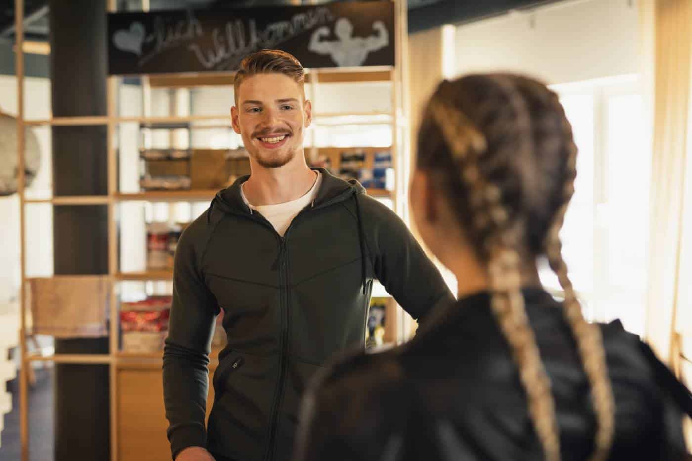 Coach talking to young woman at front desk of a gym