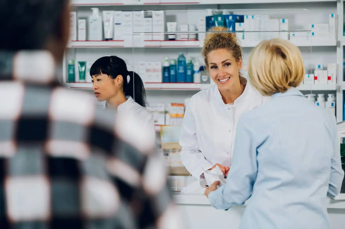 Portrait of a woman pharmacist selling drug to a senior customers in a pharmacy